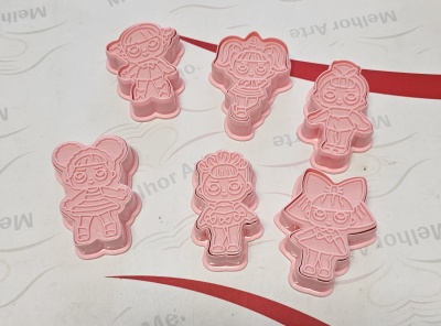 Seis moldes rosa para biscoitos com formas de personagens sobre superfície branca com texto cinzento e vermelho.