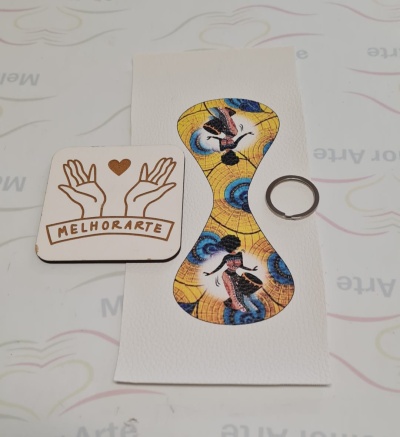 Marcador de livros em pele branca com padrão colorido, porta-chaves metálico e quadrado de madeira com desenho e texto MELHORARTE