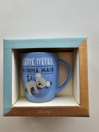 Caneca azul com desenho de coala a dormir e texto em português dentro de caixa colorida