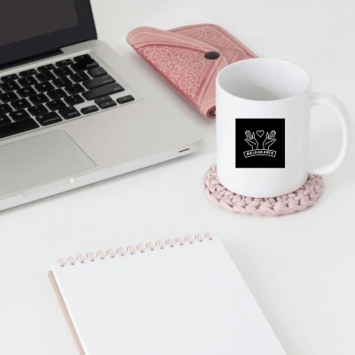 Caneca branca com logotipo preto MELHORARTE ao lado de portátil e caderno