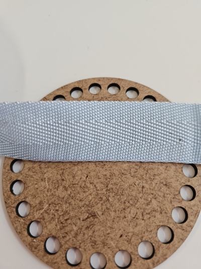 Tira de tecido cinzento claro sobre suporte redondo de madeira com orifícios