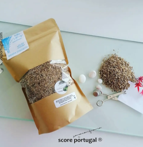 Sacola de papel com sementes, cápsulas e tesoura sobre mesa de vidro