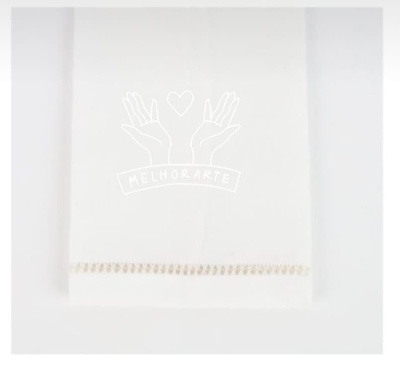 Toalha branca com bordado bege na extremidade sobre fundo branco.