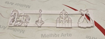 Conjunto de cortadores de massa brancos com formas de cavalo, chave, castelo e vestido sobre superfície clara