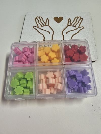 Caixa transparente com contas coloridas em forma de flor e desenho de mãos e coração