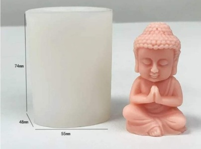Molde cilíndrico branco ao lado de figura rosa do Buda em posição de meditação