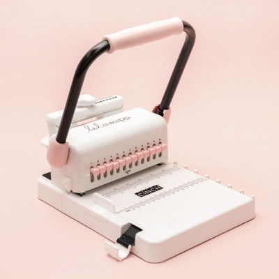aparelho de encadernação branco e rosa sobre fundo rosa