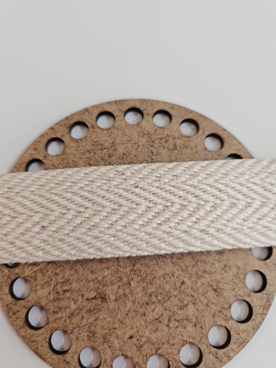 Tira de tecido bege com padrão em ziguezague sobre disco de madeira furado