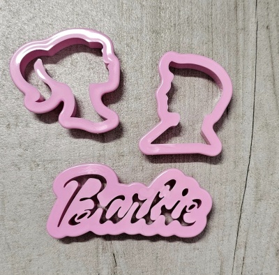 Cortadores de biscoitos rosa com silhuetas de rostos e texto Barbie