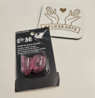 Dedos de goma flexível rosa em embalagem preta junto a cartão branco com logo MELHORARTE