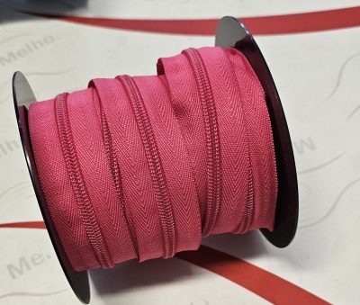 Rolo de zíper rosa em plástico preto sobre fundo branco com texto parcial e linhas vermelhas