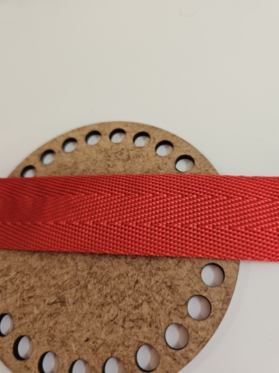 Fita vermelha texturizada sobre placa circular de cortiça com furos