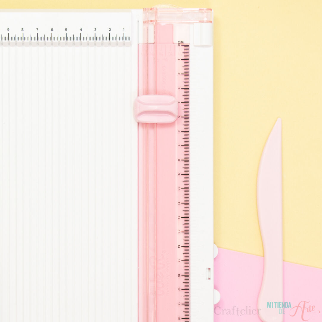 Instrumento de corte rosa e branco com espátula cor-de-rosa sobre superfície amarela