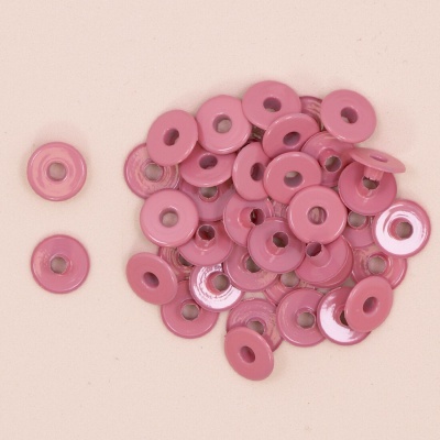 Rebites cor de rosa brilhantes com anel metálico no centro sobre fundo rosa claro