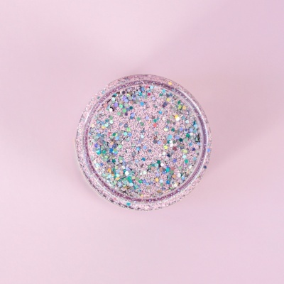 Frasco pequeno com glitter colorido em fundo rosa