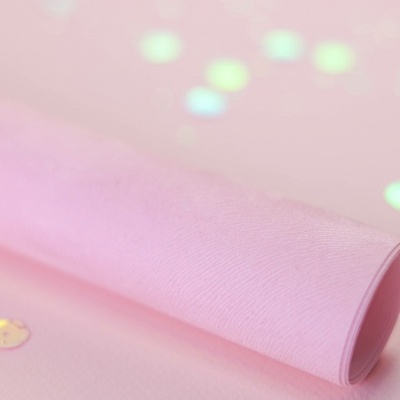 Rolo de papel cor-de-rosa com pequenos elementos redondos reflexivos dourados e roxos no fundo rosa