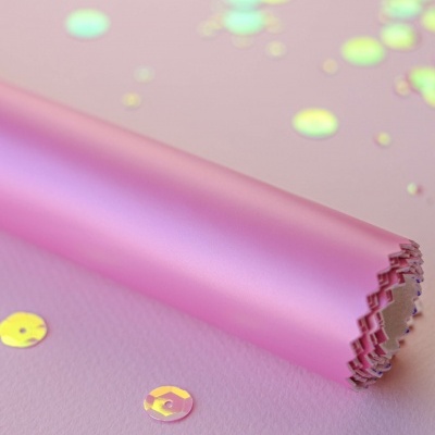 Rolo de papel rosa com brilhos holográficos sobre superfície rosa