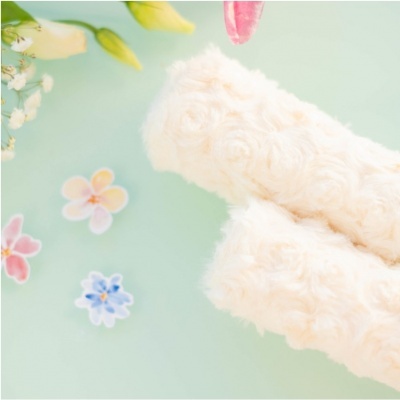 Esponjas peludas creme com flores decorativas sobre fundo verde claro