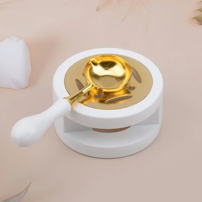 Queimador de óleo com base branca e colher dourada com cabo branco sobre superfície bege