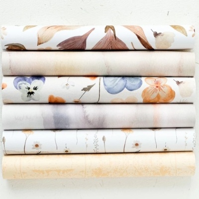 Sete rolos de tecido com padrões florais em tons pastel e creme