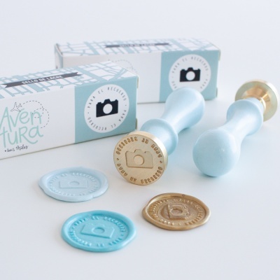 Carimbos azul claro com selos de cera em diferentes cores e caixas de embalagem ao fundo.