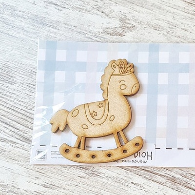 Broche de madeira com forma de cavalo de baloiço sobre fundo xadrez azul e branco