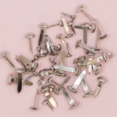 Rebites metálicos prateados sobre fundo rosa claro