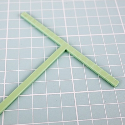 Esquadro de plástico verde em superfície quadriculada cinza