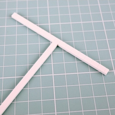 Duas réguas brancas em forma de T sobre superfície verde quadriculada