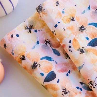 tecido floral colorido dobrado sobre superfície clara com objetos cerâmicos