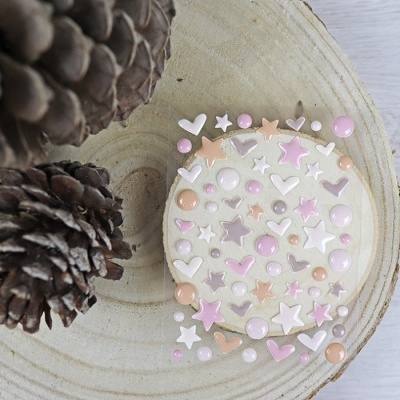 Pacote de adesivos coloridos de estrelas, corações e bolinhas sobre base de madeira com pinhas