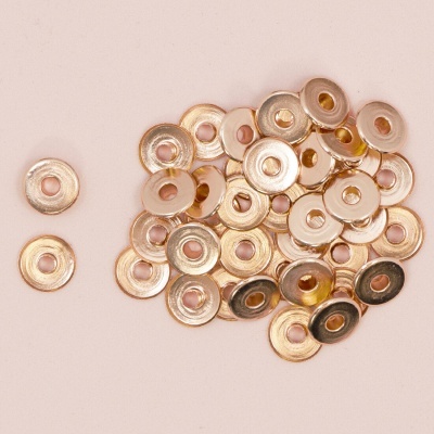 Ilhós metálicos dourados redondos sobre superfície bege