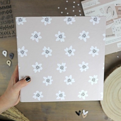 Caixa bege com flores brancas estilizadas e centro preto