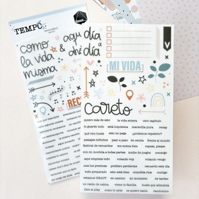 Folha decorativa com textos em espanhol e elementos gráficos coloridos sobre superfície clara e papel com padrões ao fundo