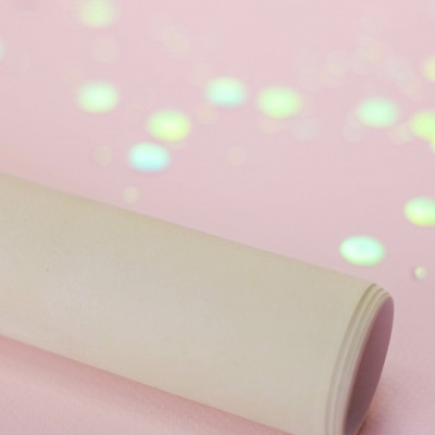 Objeto cilíndrico branco sobre fundo rosa com brilhos coloridos