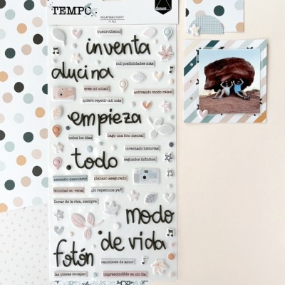 Selo acrílico com letras e frases em espanhol, símbolos pequenos, e papéis coloridos com padrões