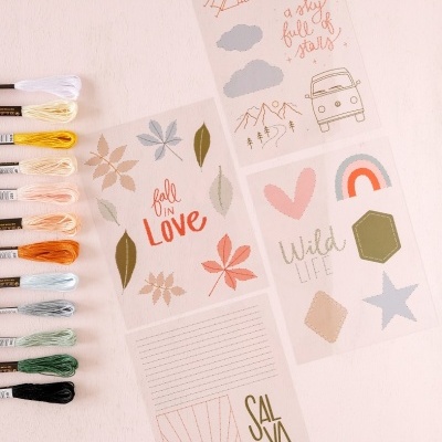 Linhas de bordar coloridas ao lado de folhas ilustradas com textos e desenhos em fundo claro