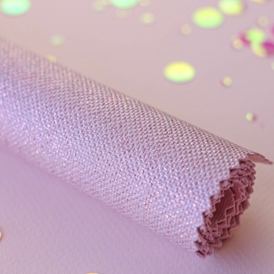 Rolo de tecido lilás brilhante com textura fina junto a lantejoulas coloridas sobre fundo lilás