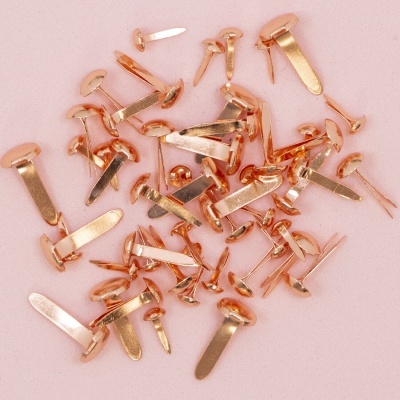 Várias tachas metálicas douradas em fundo rosa claro