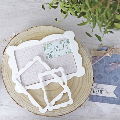 Molduras brancas decorativas sobre base de madeira com etiqueta 'be authentic' e tecidos azuis com etiqueta 'follow your HEART'