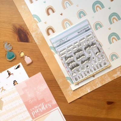 Conjunto de carimbos, papel decorativo com arco-íris, clips decorativos e mesa de madeira