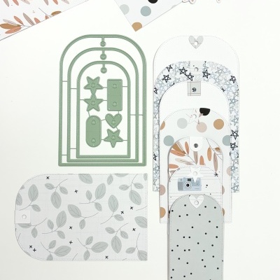 Moldes de corte para artesanato em metal verde e papéis estampados variados sobre fundo branco