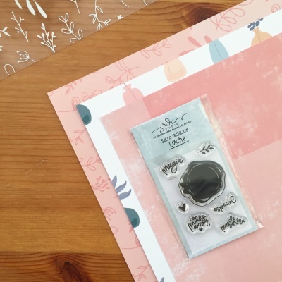 Conjunto de selos acrílicos transparentes com palavras e desenho, sobre papéis decorativos rosa e branco