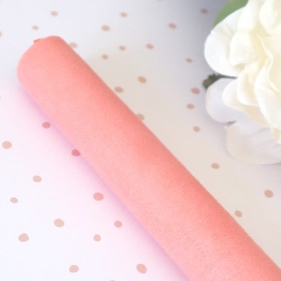 Produto cilíndrico rosa liso sobre fundo branco com pontos rosa e flor branca