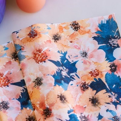 Pano de tecido com padrão floral colorido sobre superfície branca.