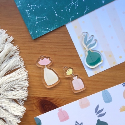 Moldes acrílicos de flores decorativas sobre mesa de madeira com papéis e tecido ao redor