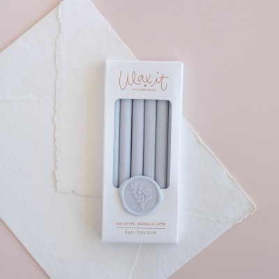 Pacote branco com seis velas cinzentas finas da marca Wax it