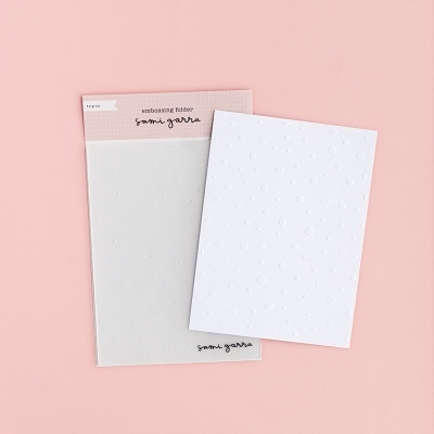 Embossing folder branco com padrão de bolinhas em relevo sobre fundo rosa
