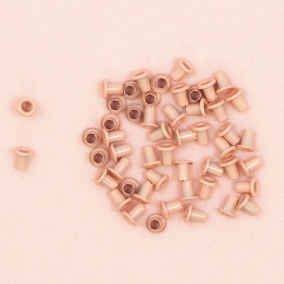 Conjunto de ilhós de metal cobre sobre superfície rosa