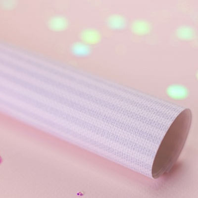 Rolo de papel texturizado branco sobre fundo cor-de-rosa com lantejoulas.